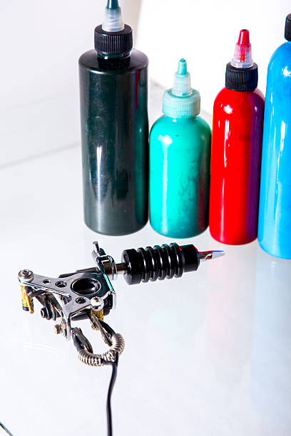 Tattoo gun with ink tubes on white background stock photo