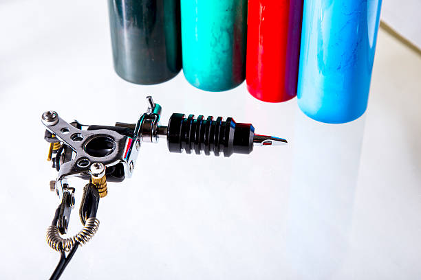 Tattoo gun with ink tubes on white background stock photo