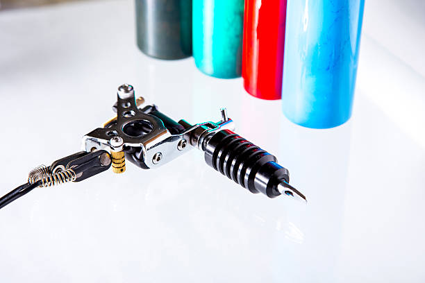 Tattoo gun with ink tubes on white background stock photo