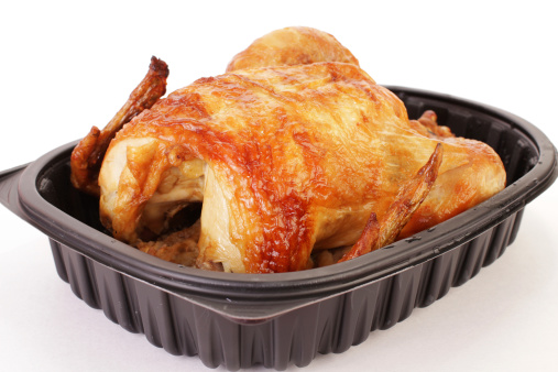 Rotisserie Chicken Dinner cooked and packaged by grocery store and brought home ready to serve.  Still in plastic contain against white background.