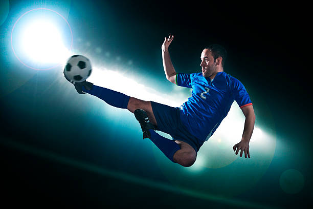 joueur de football dans l'air de frappe la balle - sporting position vitality blurred motion strength photos et images de collection