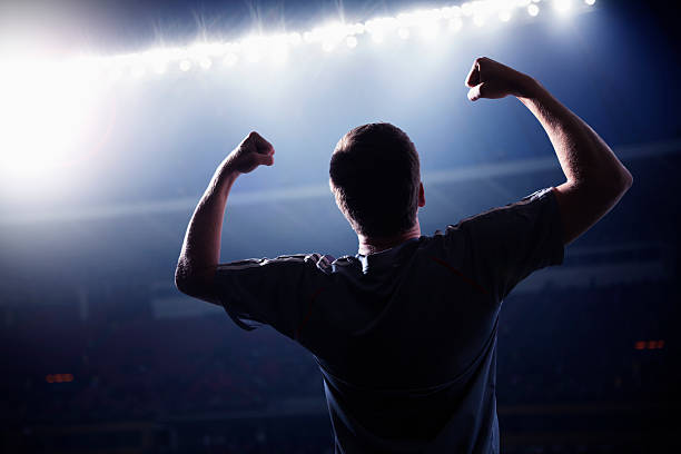 Soccer player cheering with his arms raised in the stadium stock photo