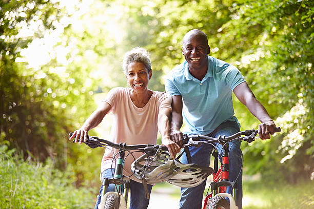 madura afro-americana casal em passeio de bicicleta em campo - african descent cycling men bicycle - fotografias e filmes do acervo