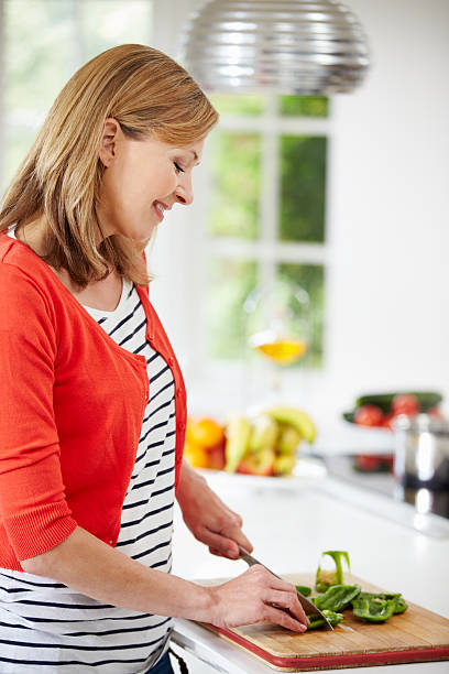 istock Woman Standing At Counter Preparing Meal In Kitchen 460451643
