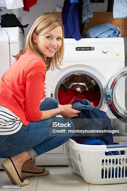 Woman Loading Clothes Into Washing Machine Stock Photo - Download Image Now - Mature Women, Washing Machine, 40-49 Years