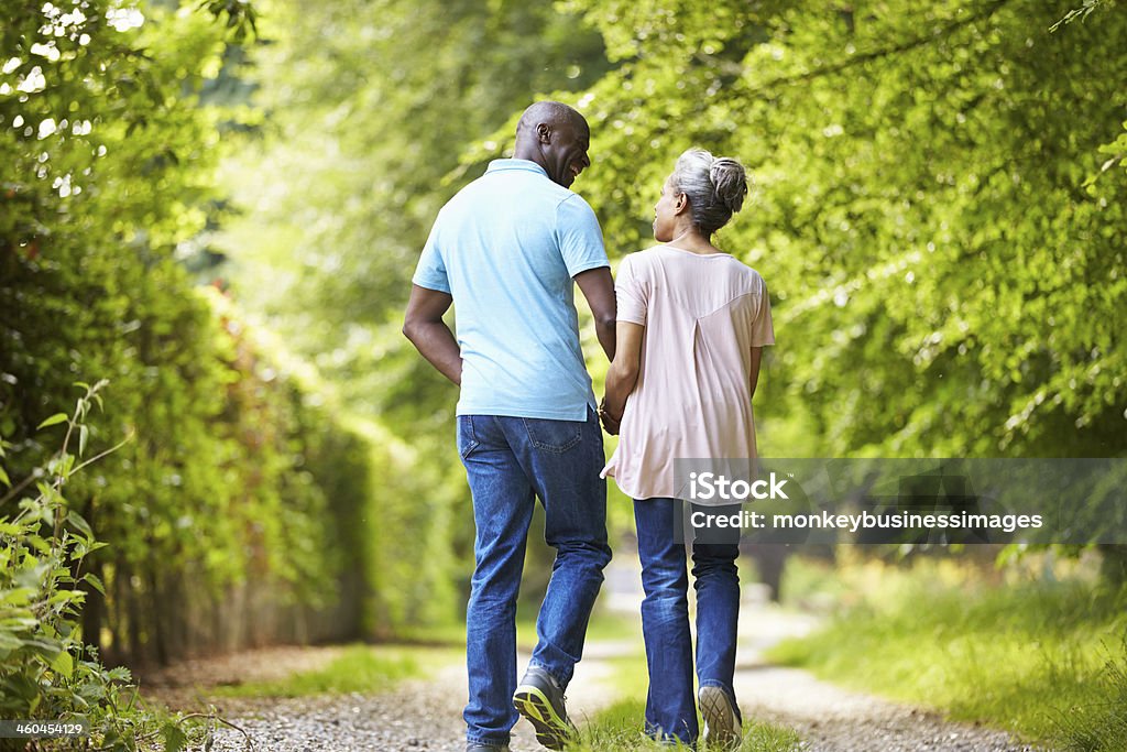 Mature African American Couple Walking In Countryside Rear View Of Mature African American Couple Walking In Countryside Walking Stock Photo