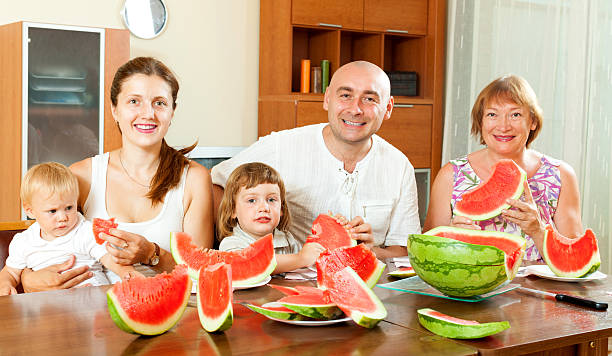 istock Smiling happy family together with watermelon over dining table 460463103