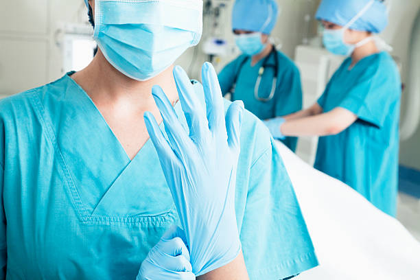 istock Female surgeon putting on gloves in the operating room, midsection 460473985