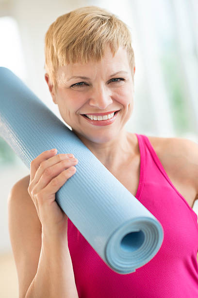 istock Woman Holding Rolled Up Exercise Mat At Gym 460476247