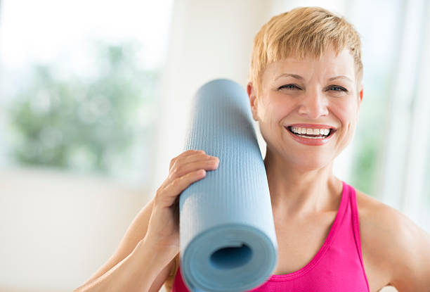 istock Cheerful Woman Holding Rolled Up Exercise Mat 460476249