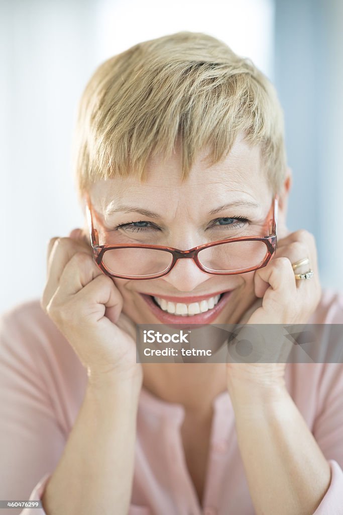 Smiling woman with red glasses positioned on nose bridge Close-up portrait of happy mature woman wearing eyeglasses 50-54 Years Stock Photo
