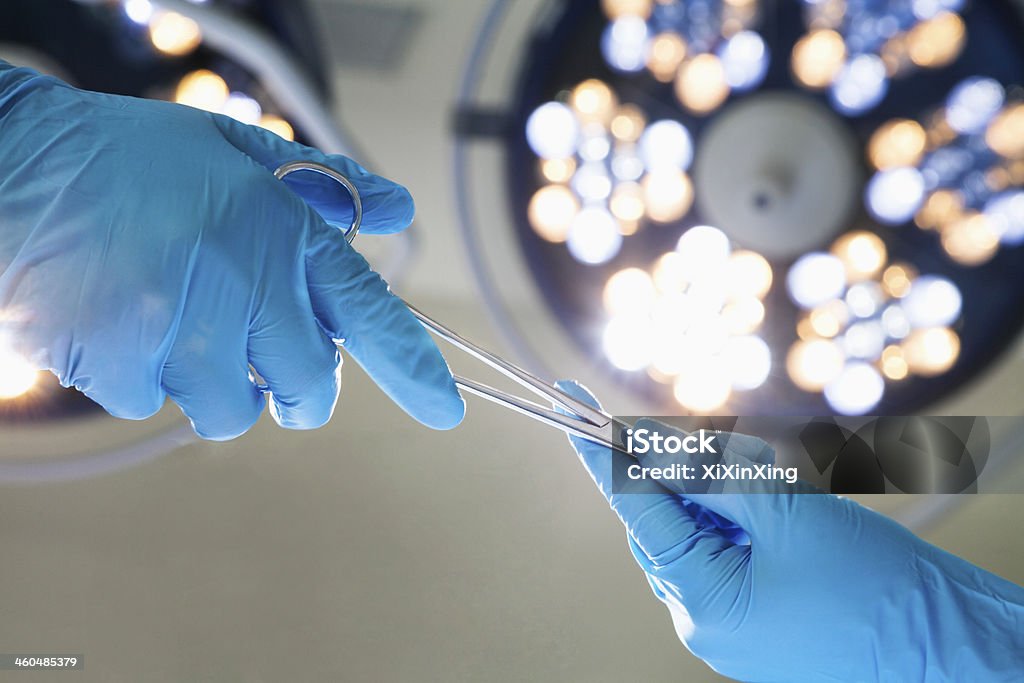 Close-up of gloved hands passing the surgical scissors Close-up of gloved hands passing the surgical scissors, operating room, hospital Operating Room Stock Photo