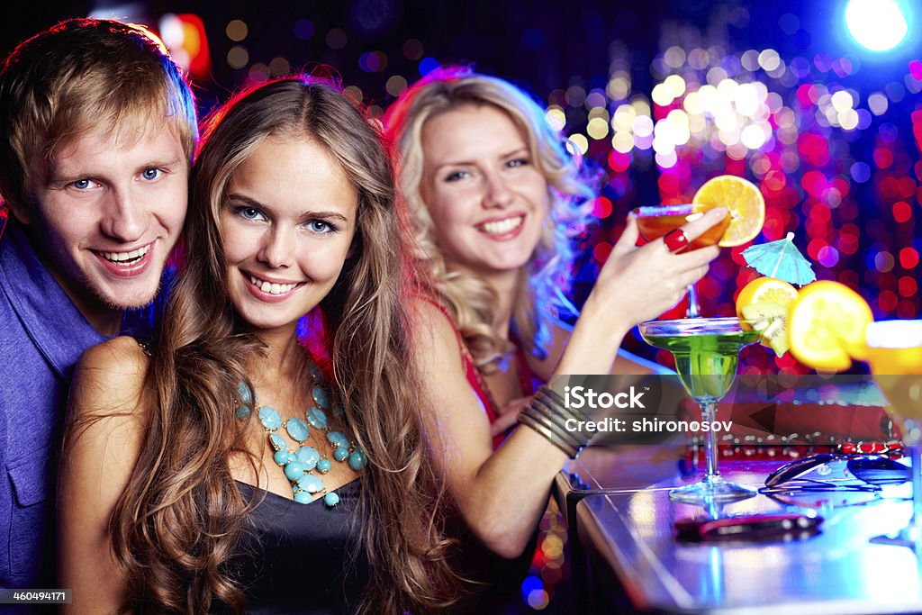 Friendly clubbers Image of happy girl looking at camera with her friends near by Adult Stock Photo