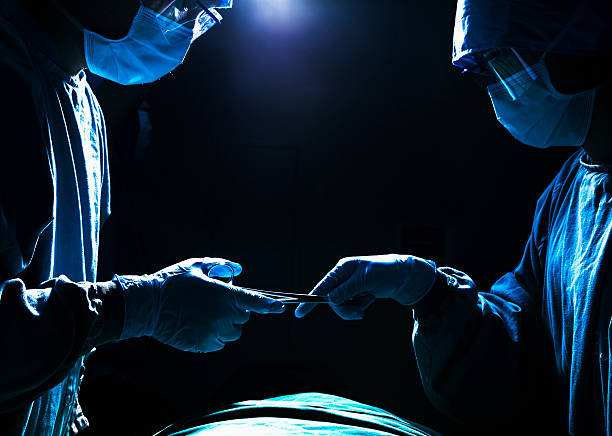 cirurgiões passando equipamento cirúrgico na sala de cirurgia, escuro - beijing opera mask china - fotografias e filmes do acervo