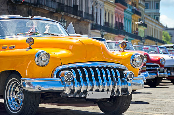 Vintage American car parked on street in Havana Vieja, Cuba. Dilapidated buildings in traditional colonial style are visible in the background, 50 megapixel image.