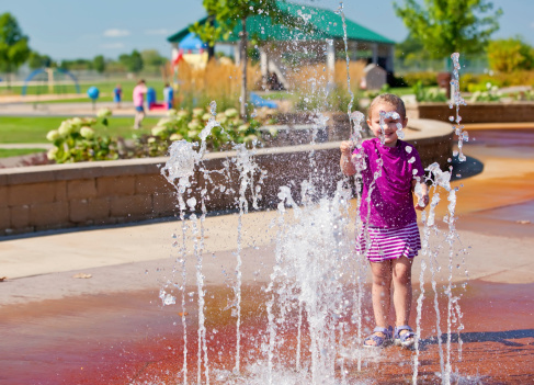 Young girl playing in the fountains at the splash park.
