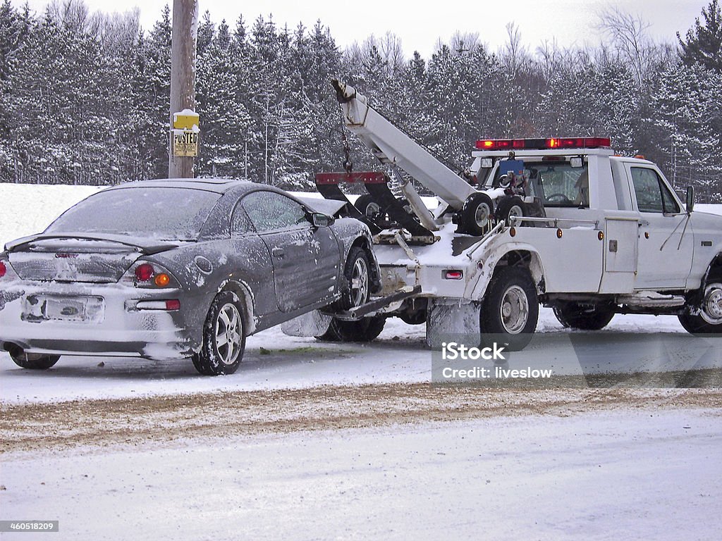 tow truck towing car Tow truck hauling a wrecked car away in winter. Tow Truck Stock Photo