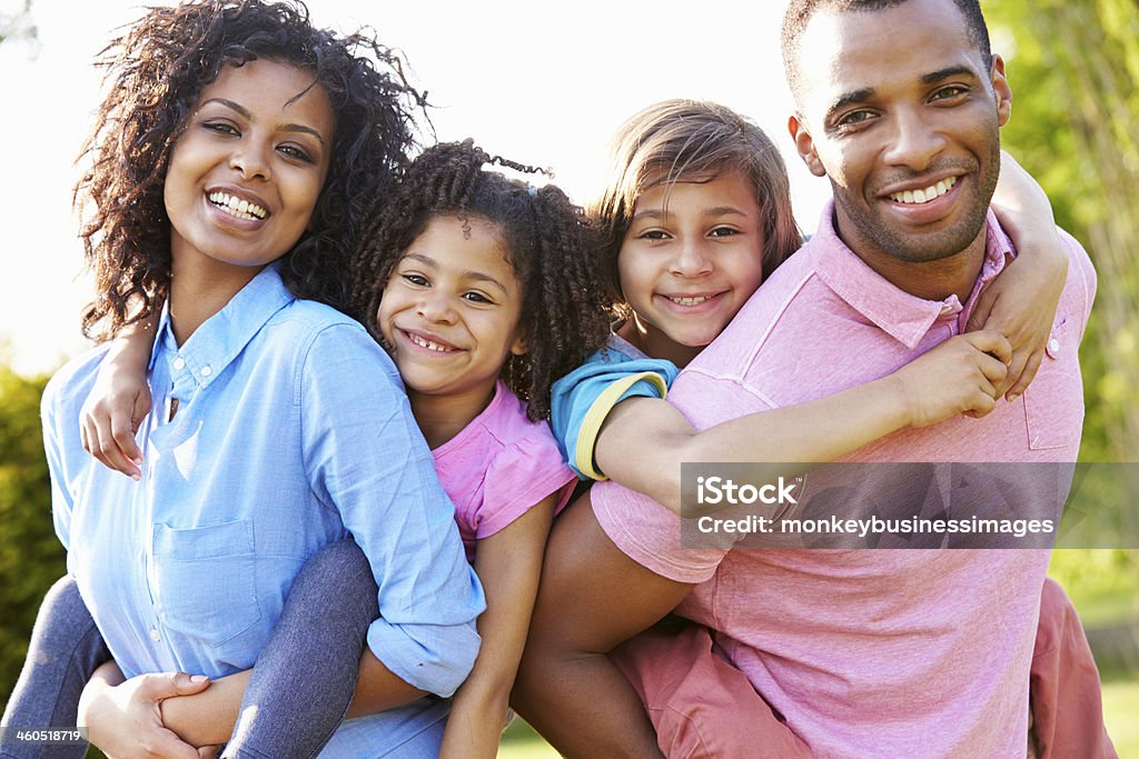 African American Parents Giving Children Piggyback Rides African American Parents Giving Children Piggyback Rides Smiling At Camera Family Stock Photo