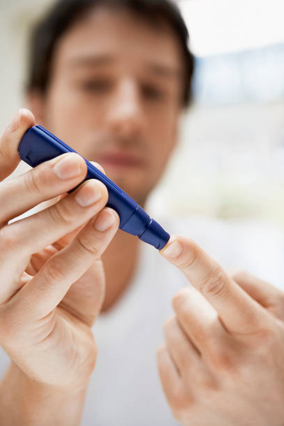 istock Close-up of man's hands using a blue lancet on his finger 460532743