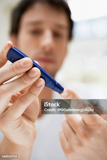 Closeup Of Mans Hands Using A Blue Lancet On His Finger Stock Photo - Download Image Now