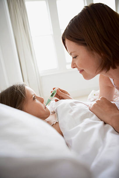 istock Mother Checking Temperature Of Daughter In Bed 460545601