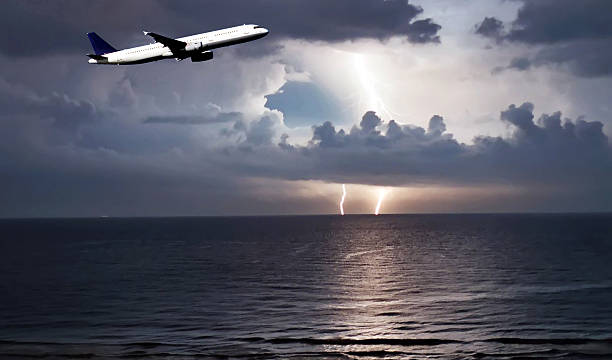 Airplane in the storm night view of an airplane frlying over the ocean with a storm to the bottom of the image Microburst stock pictures, royalty-free photos & images