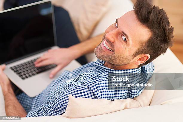 Smiling Man Using Computer In Living Room Stock Photo - Download Image Now - Adult, Adults Only, Beautiful People