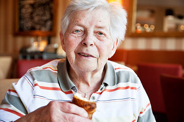 senior woman, 88 years old, sitting in a cafe and eating