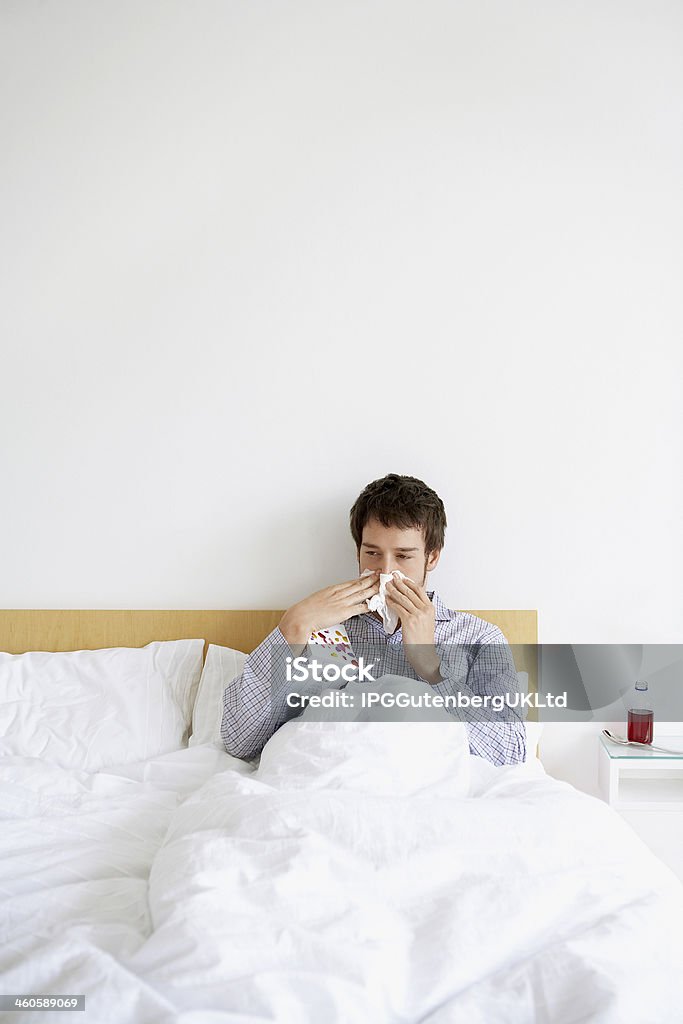 Man With Cold Blowing Nose In Bed Young man with cold blowing nose in bed Adult Stock Photo