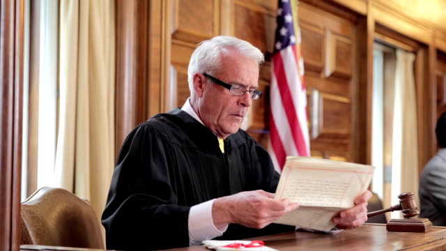 Judge banging gavel at bench in courtroom
