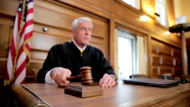 Judge banging gavel on bench in courtroom