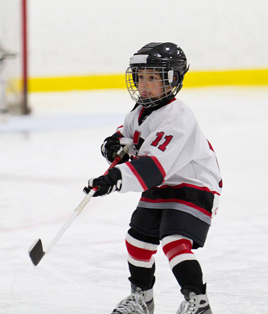 Child making a pass while playing ice hockey stock photo