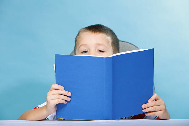 istock child boy kid reading a book on blue 460642375