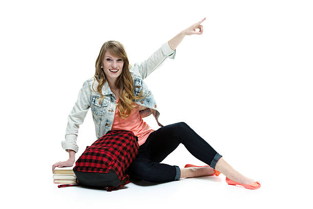 istock Smiling student pointing above and sitting on floor 460646587