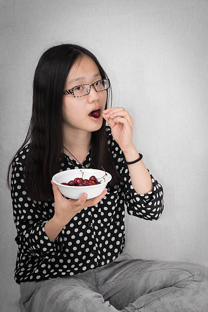 Girl eating a bowl of cherry stock photo