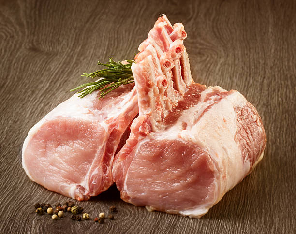 Uncooked lamb chops on a wooden cutting board with seasoning stock photo