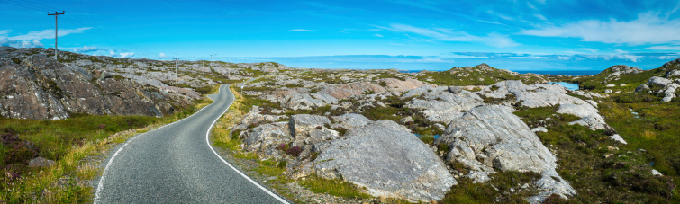 Country road winding its narrow way over the remote island landscape, between blue ocean and heather clad mountains of the Isle of Harris in the Western Isles, Scotland, UK. ProPhoto RGB profile for maximum color fidelity and gamut.