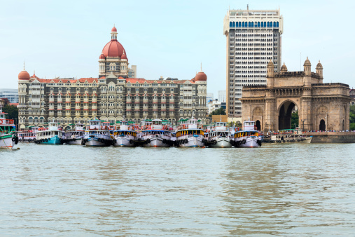 Boats in Mumbai Harbour with the Taj Mahal Palace Hotel & Towers and Gateway of India in the background.