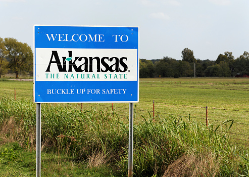 Maysville, Arkansas, USA – October 4, 2012: A welcome sign marks the state line between Arkansas and Oklahoma on Arkansas SR 14. Known as “The Natural State,” Arkansas is located in the southeastern United States.