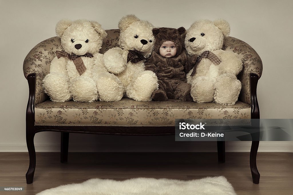 Baby Cute baby in bear costume sitting on sofa with Teddy bears Animal Stock Photo