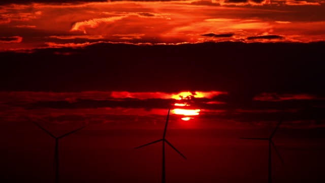 Wind turbines against red sunset