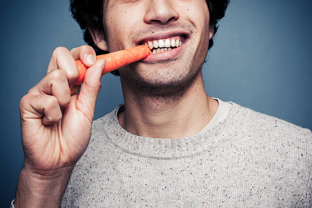 Young man eating a carrot stock photo