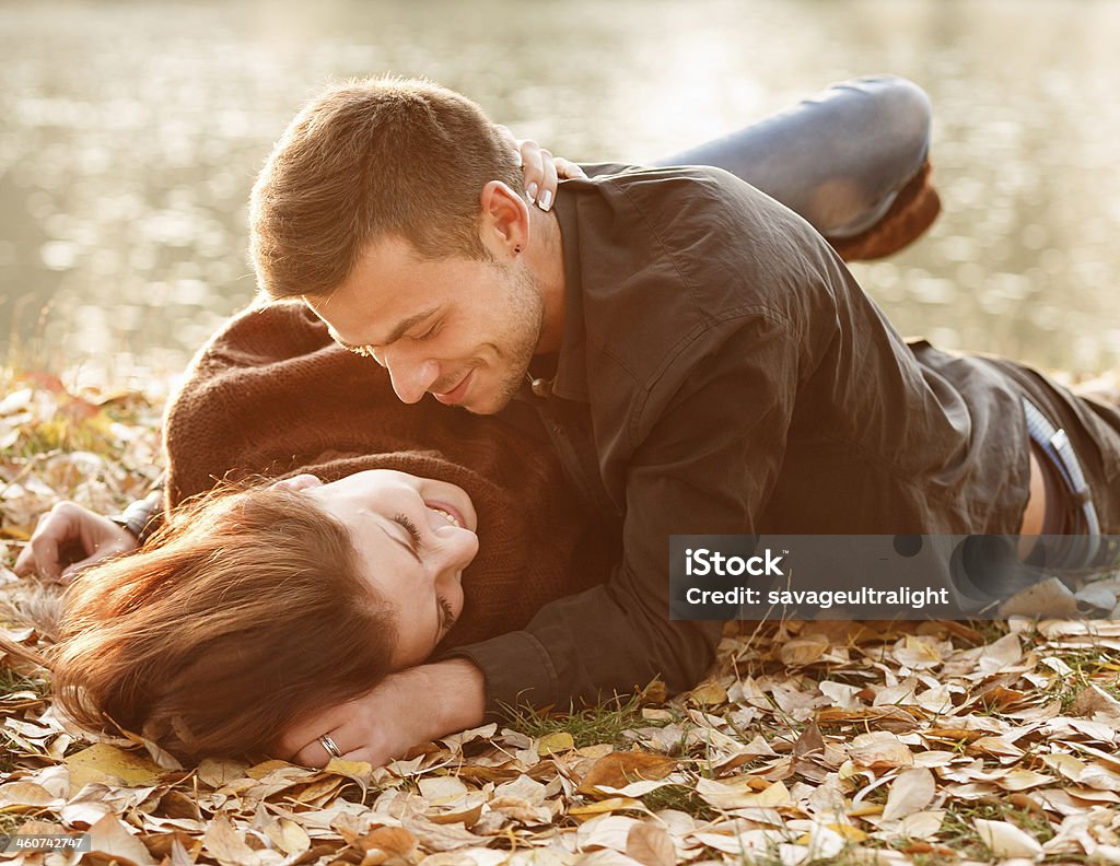 young couple lying down smiling young couple lying down near lake smiling having good time 20-29 Years Stock Photo