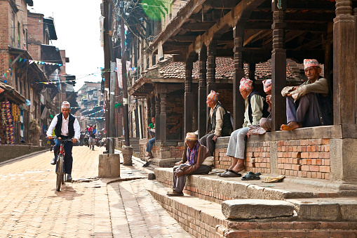 Bhaktapur, Nepal - May 20, 2013: Unidentified Tharu old men besides the street of Bhaktapur, Nepal on May 20, 2013. Tharu are an ethnic group from west part of Nepal.