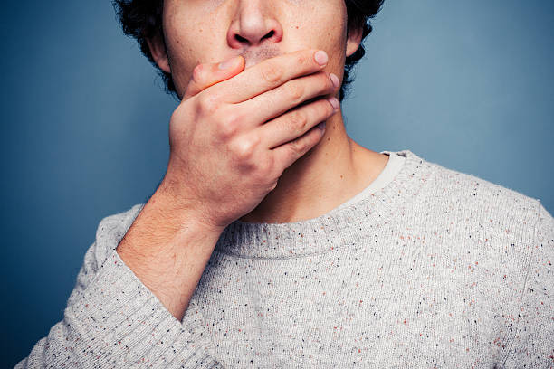 Shocked young man covering his mouth stock photo
