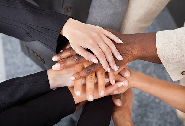 Multiracial Businesspeople Stacking Hands High Angle View Of Multiracial Businesspeople Stacking Hands Over Each Other stacked hands photos stock pictures, royalty-free photos & images