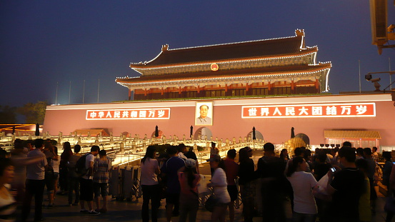 Beijing, China – May 21, 2012: The Entrance to the forbidden city with Portrait of Mao. There are locals and tourists in front of the entrance.  The portrait on the wall is Chairman Mao Zedong, and the text on each side reads \