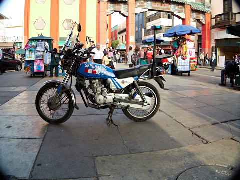Lima, Peru - June 3, 2013: Peruvian police motorcycle parked in Lima Chinatown district. People are pictured walking in the background