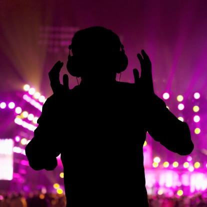 Silhouette of DJ wearing headphones and performing at a night club