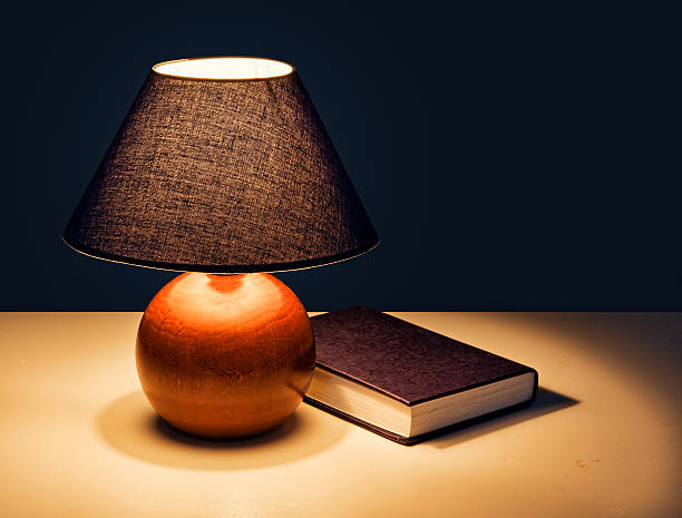 istock Bedtime reading - lamp with book at night 460808109